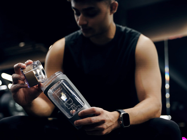Mann füllt in einem Fitnessstudio Wasser in einen elektrischen STARKSHAKE Shaker
